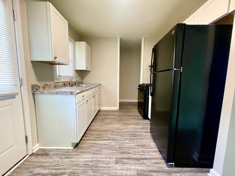 a kitchen with white cabinets and a black refrigerator
