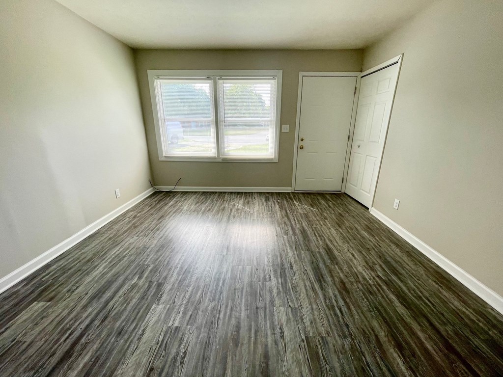 an empty living room with vinyl flooring and a window