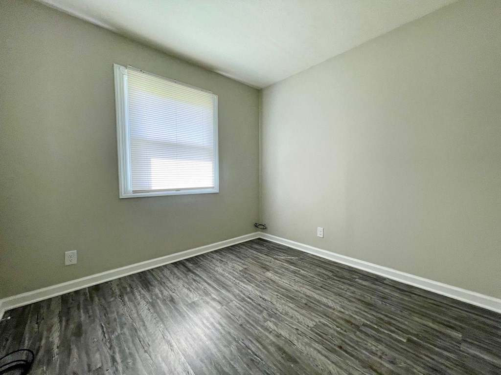 an empty room with wooden floors and a window