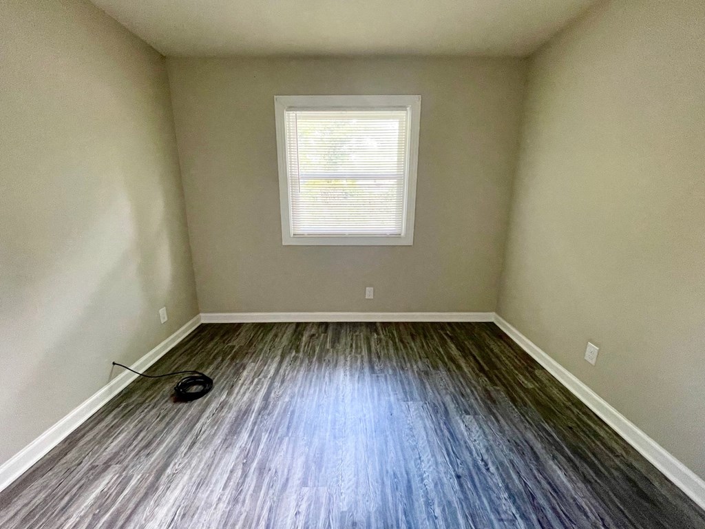 an empty room with wooden floors and a window