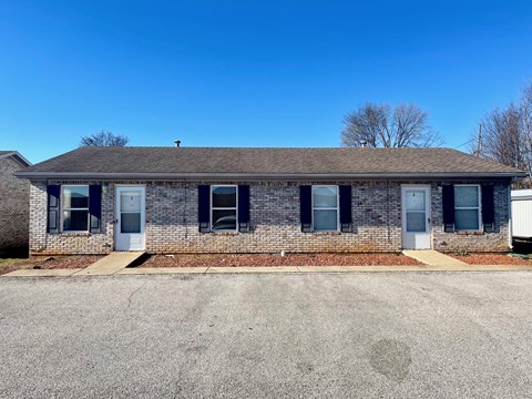 a brick house with blue shutters and a driveway