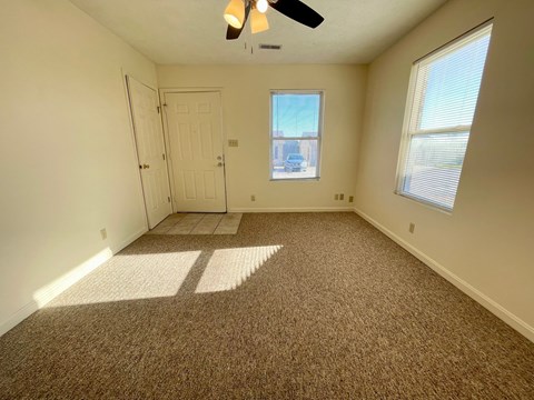 an empty living room with carpet and a white door