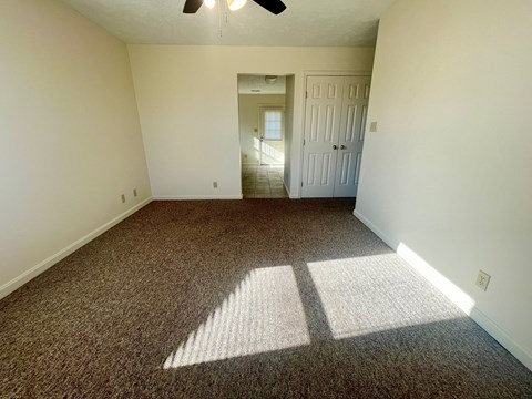 a bedroom with a carpeted floor and a door to a hallway