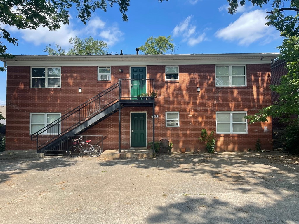 a red brick building with a green door and a bike parked outside