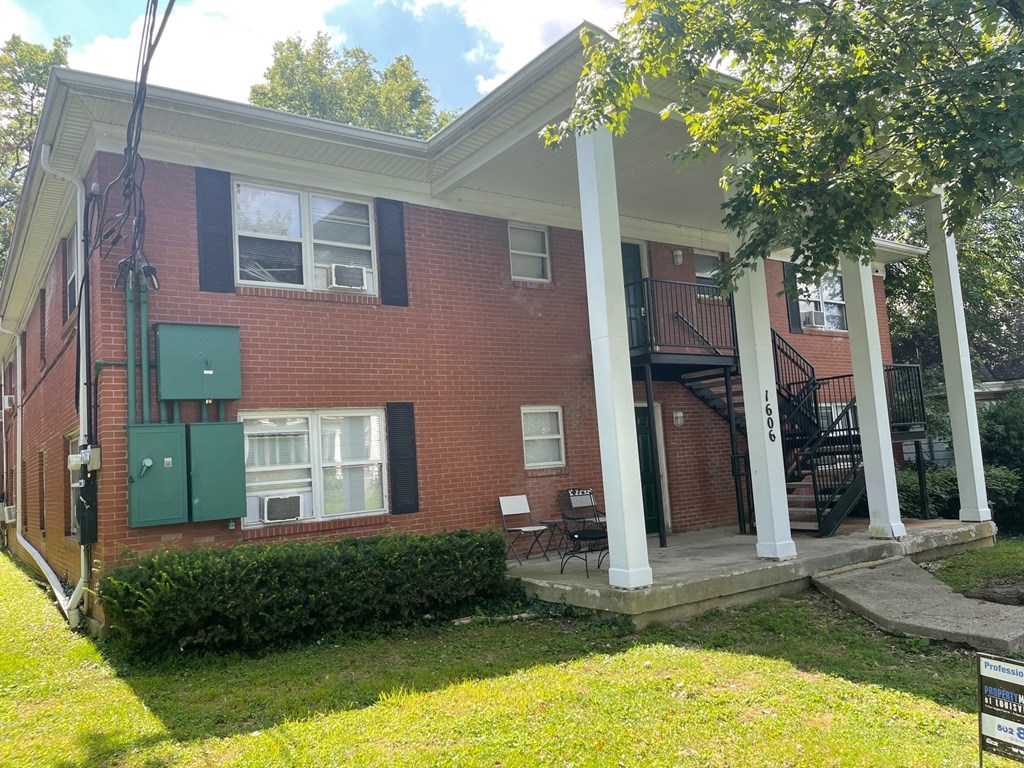 the front of a brick house with columns and a lawn
