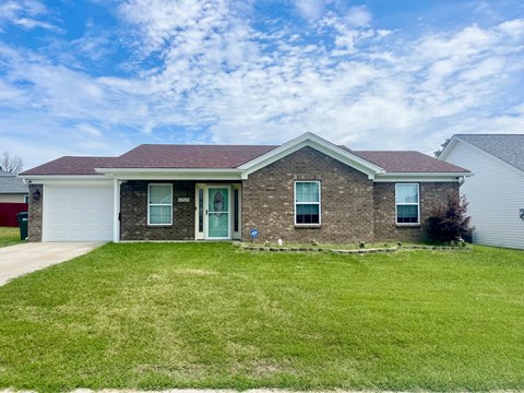 a brick house with a green lawn and a blue sky