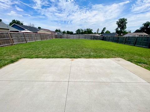 a backyard with a yard and a fence and a grassy area