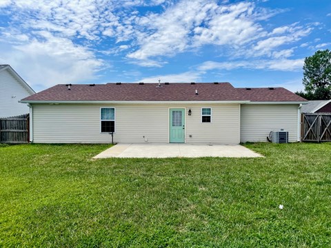 a white house with a green door and a grassy yard