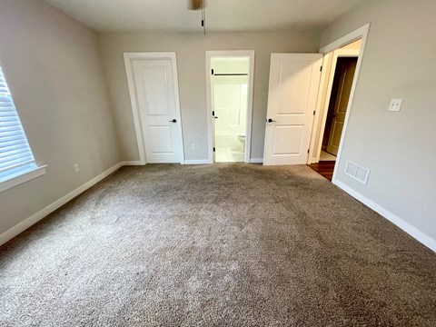 an empty living room with carpeting and white doors