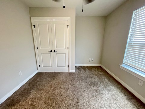 an empty bedroom with carpet and a door