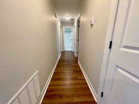 a long hallway with wood floors and white walls