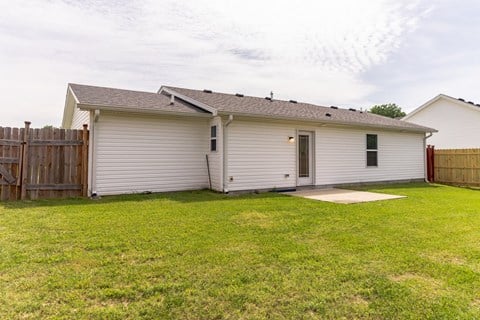a small white house with a yard and a wooden fence