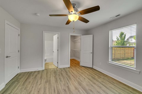 an empty living room with a ceiling fan and a window