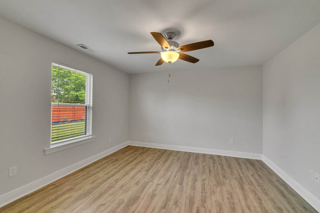 an empty living room with a ceiling fan and a window