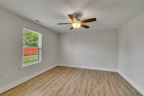 an empty living room with a ceiling fan and a window