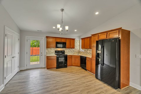 a kitchen with wooden cabinets and a black refrigerator