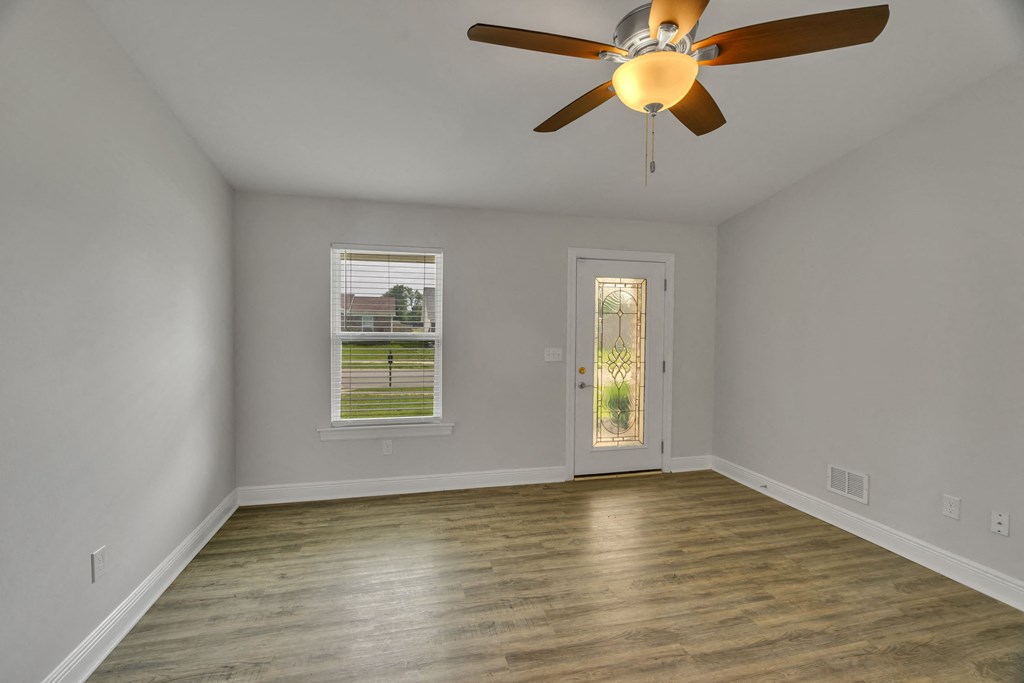 an empty living room with a ceiling fan and a door