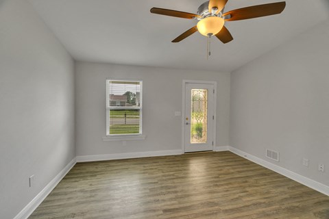 an empty living room with a ceiling fan and a door