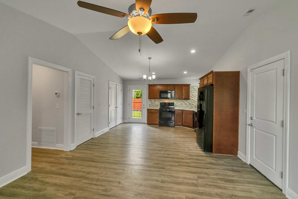 a renovated living room with a ceiling fan and a kitchen