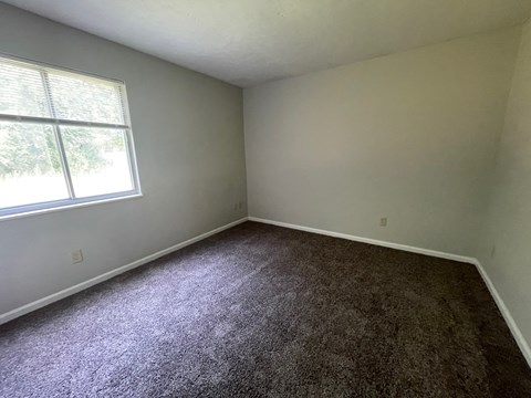 an empty room with carpet and a window