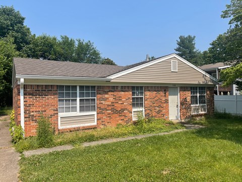 the front of a brick house with a yard and grass