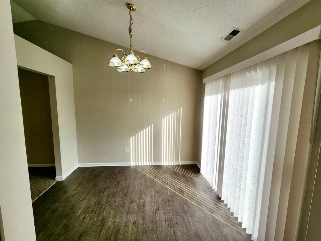 an empty living room with a large window and a chandelier