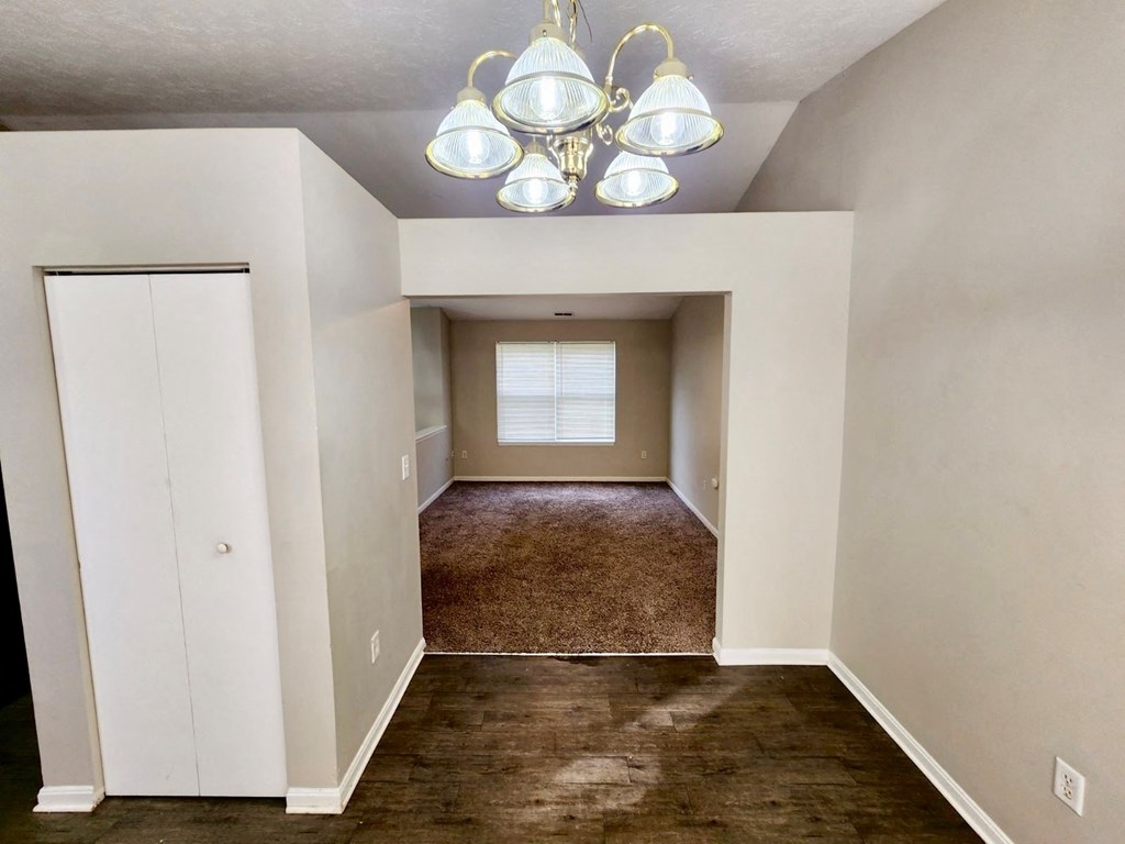 an empty living room with a chandelier and a window