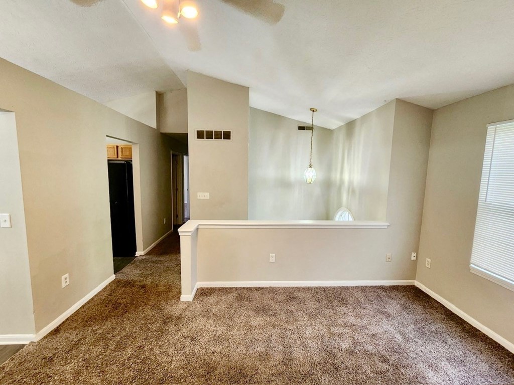 an empty living room with a large window and carpeted floor