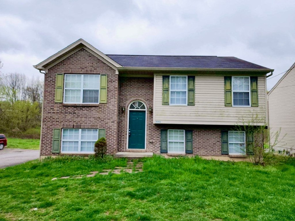 a brick house with green shutters and a green door