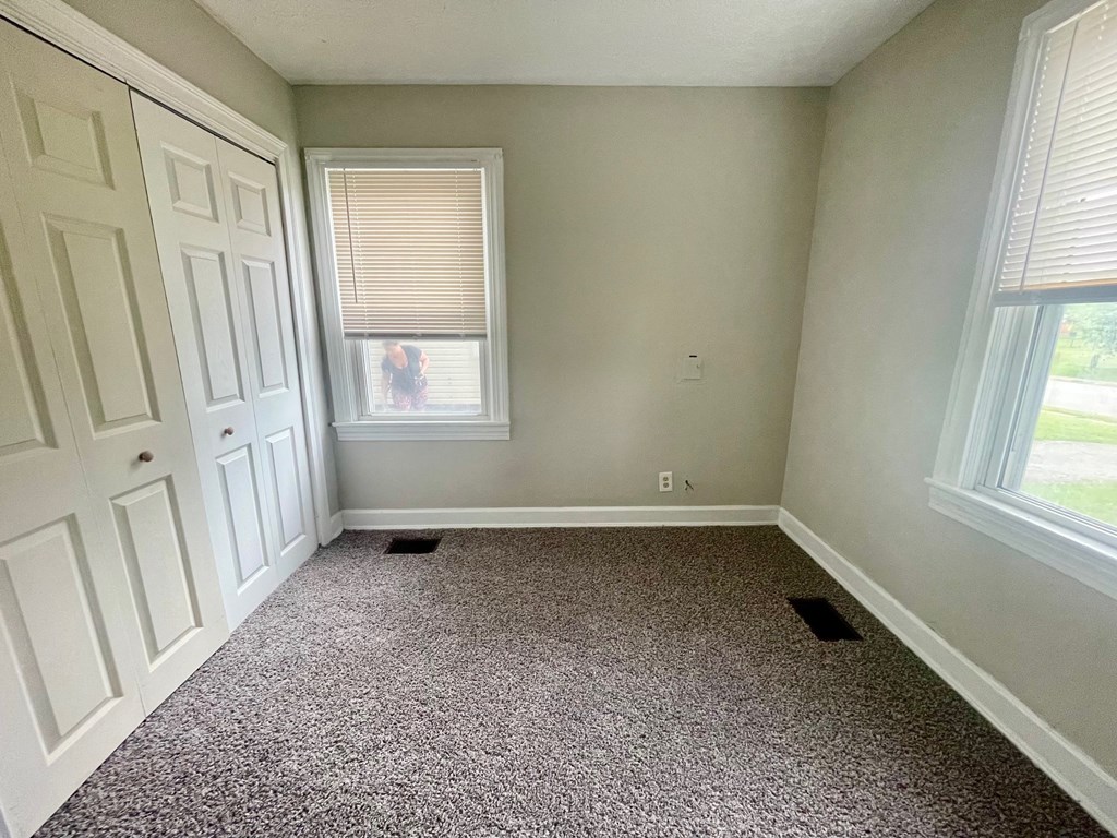 a room with carpet and two windows and a door
