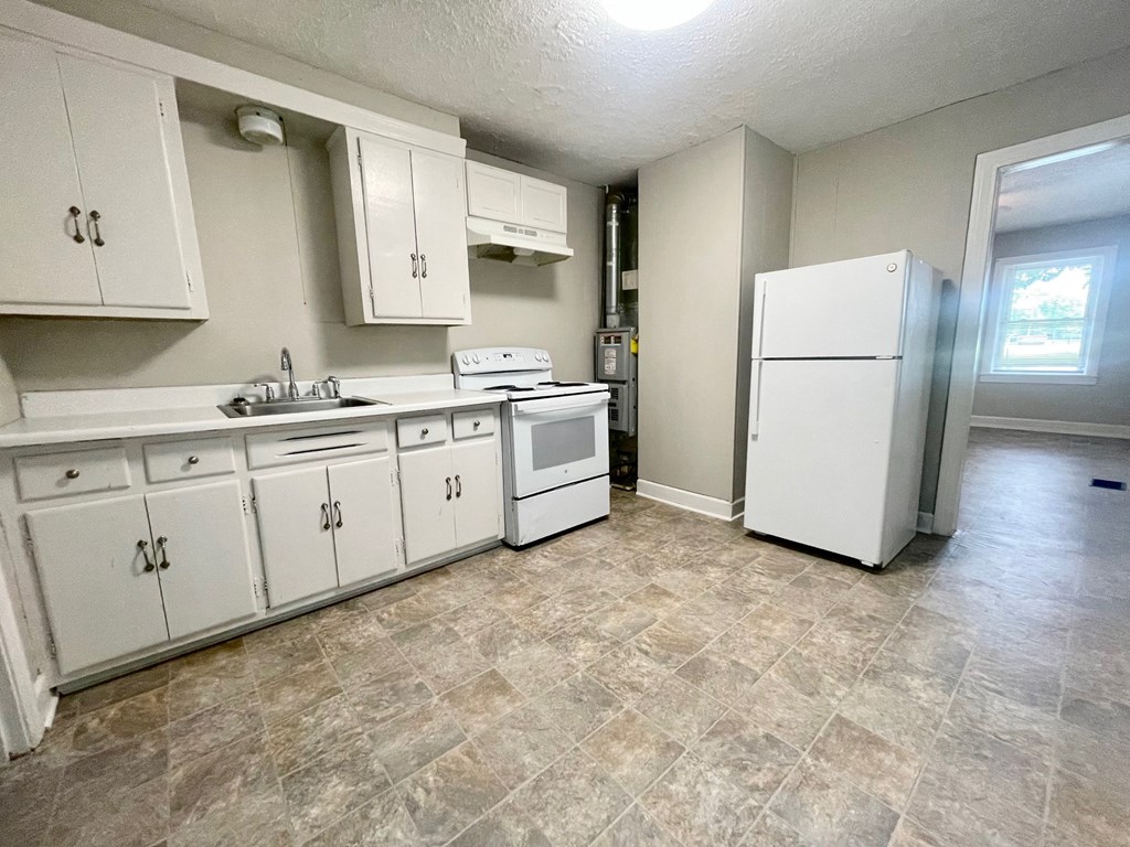 an empty kitchen with white appliances and white cabinets