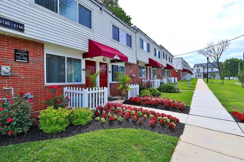the front yard of an apartment building with flowers and a sidewalk