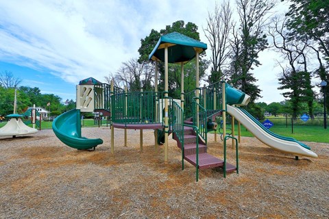 a playground with slides and chairs in a park