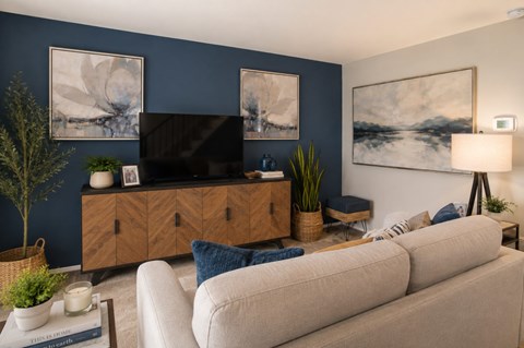 A living room with a beige sofa, a wooden cabinet, and a painting on the wall.