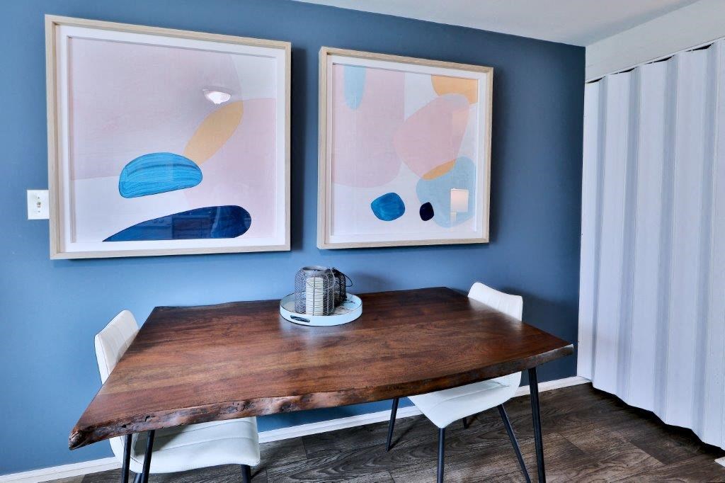 a dining room with a wooden table and two pictures on the wall