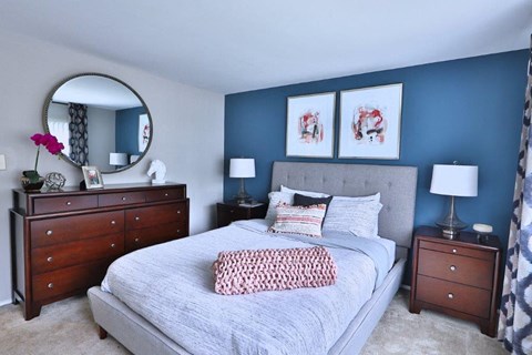 a bedroom with a bed and two dressers and a mirror