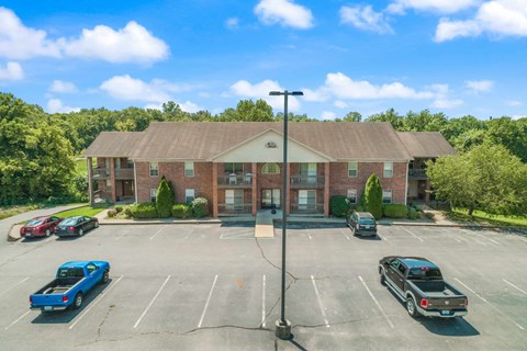 an empty parking lot in front of a brick building with cars parked in front