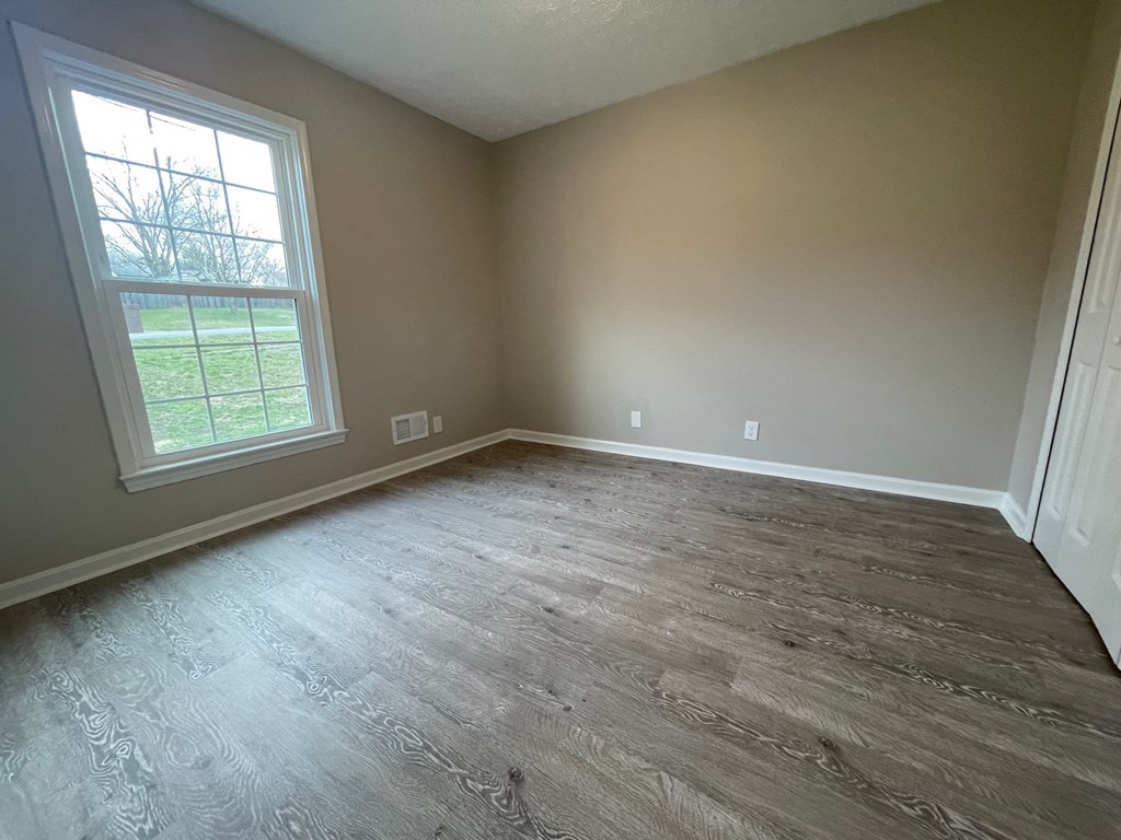 A room with a window and wooden flooring.