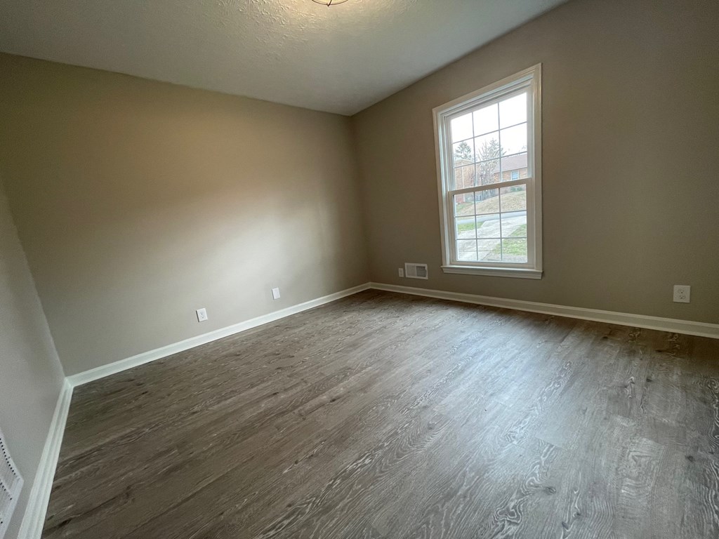 A room with a window and wooden flooring.