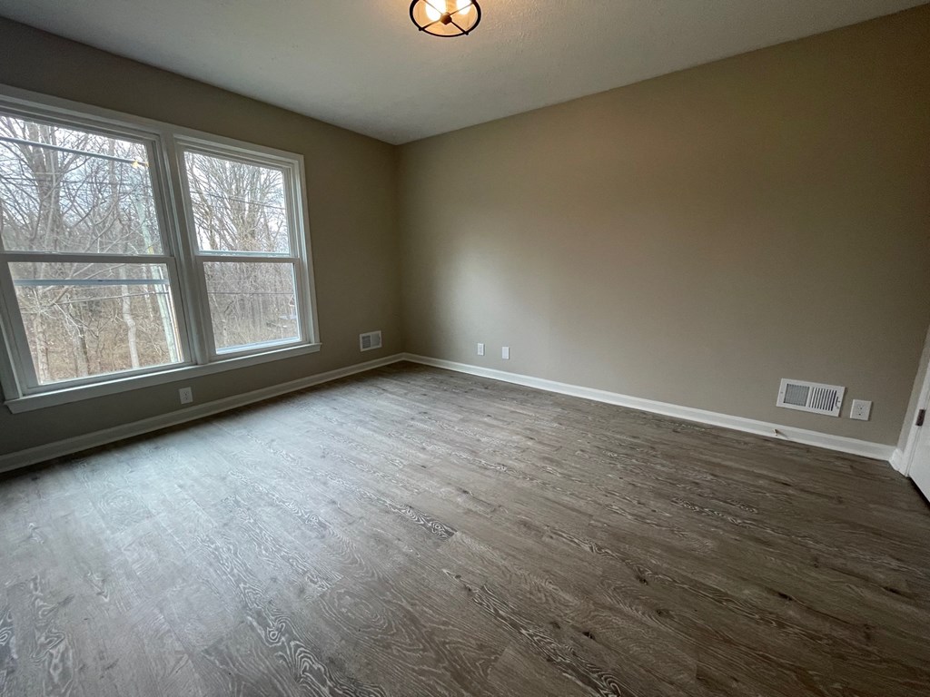 A room with a large window and wooden flooring.