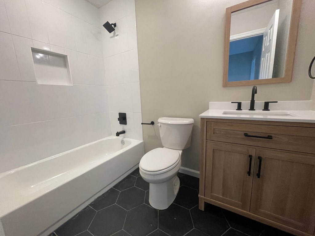 A white toilet sits next to a white bathtub in a bathroom.