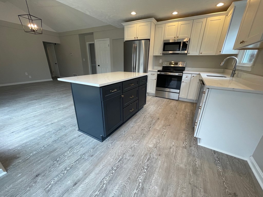 A kitchen with a black island and wooden floors.