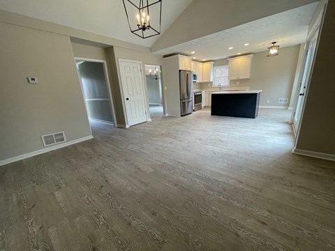 A spacious living room with a kitchen in the background.