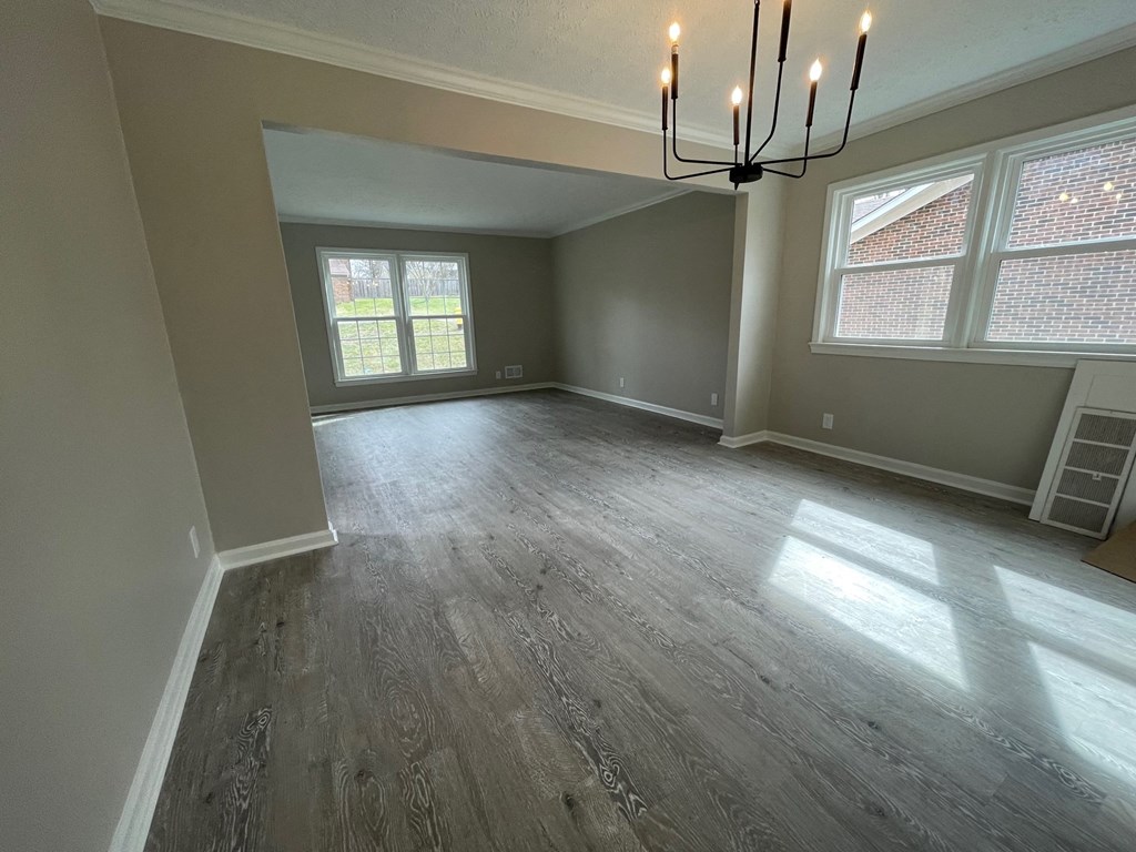 A room with a grey floor and a chandelier.