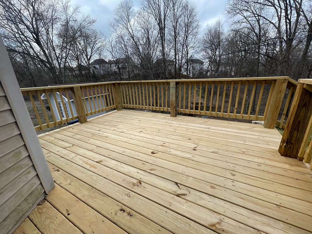 A wooden deck with a railing and trees in the background.