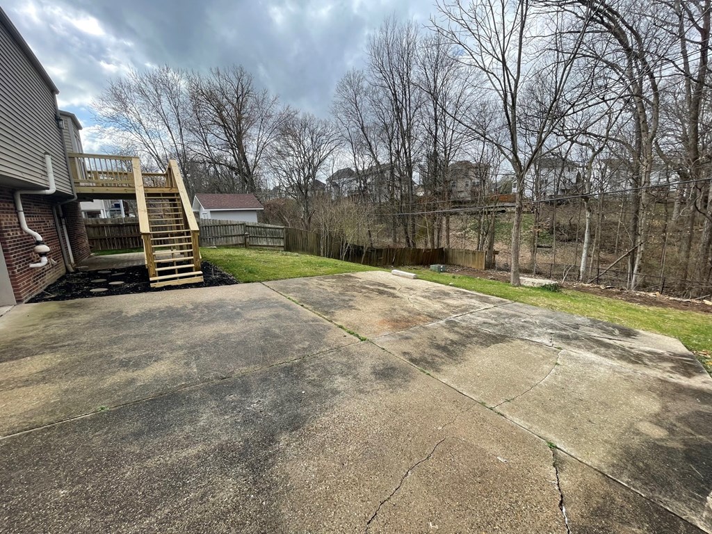 A concrete patio with a wooden staircase leading to a house.