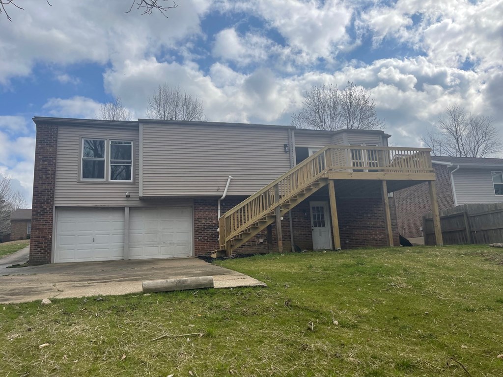 A house with a grey garage door and a wooden deck.