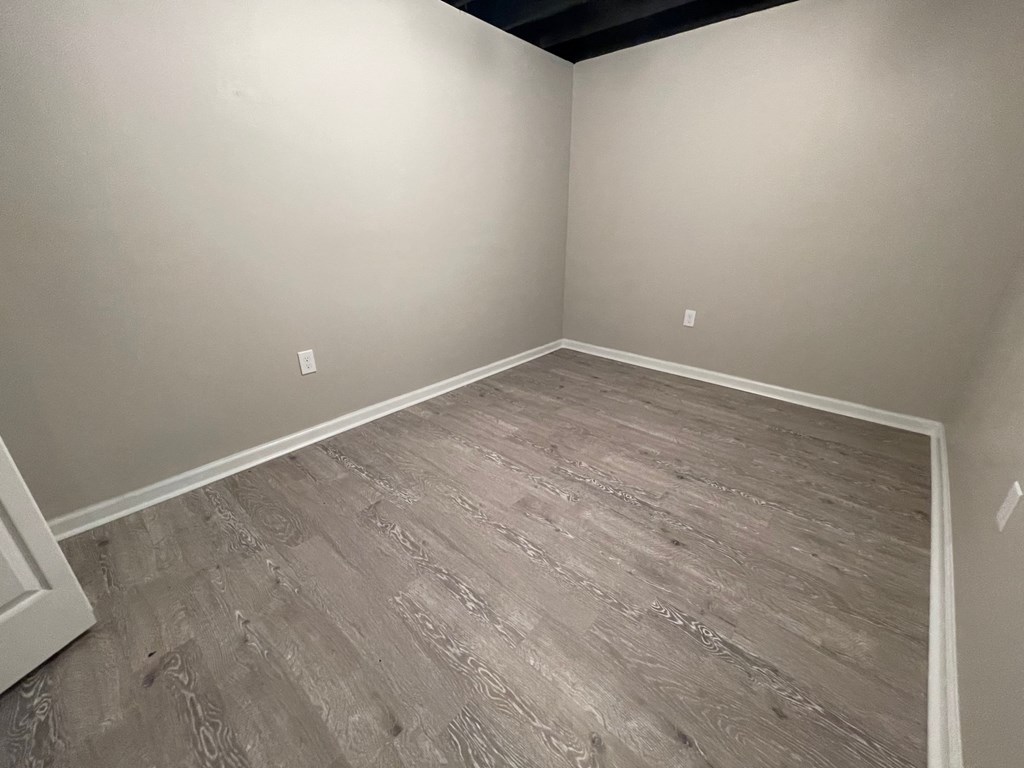 A room with wooden flooring and white walls.