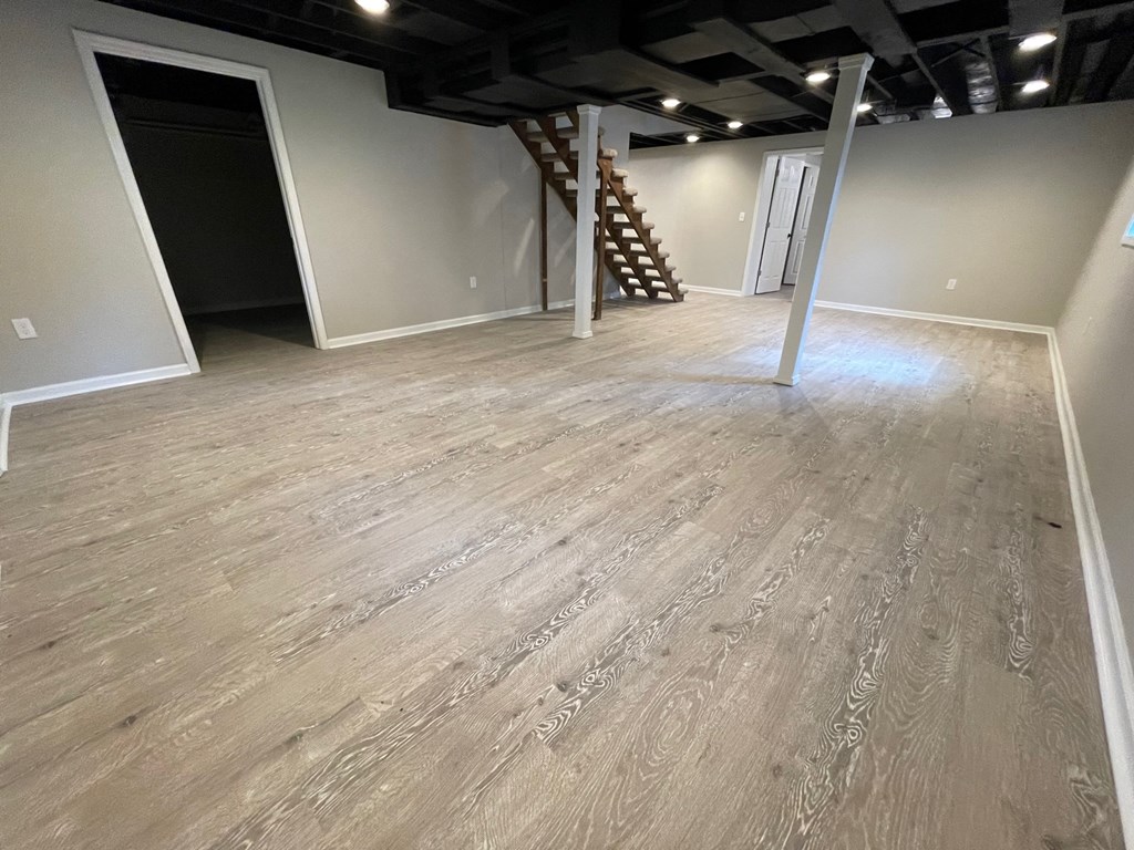 A room with wooden flooring and a staircase in the corner.