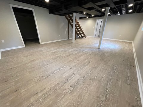 A room with wooden flooring and a staircase in the corner.